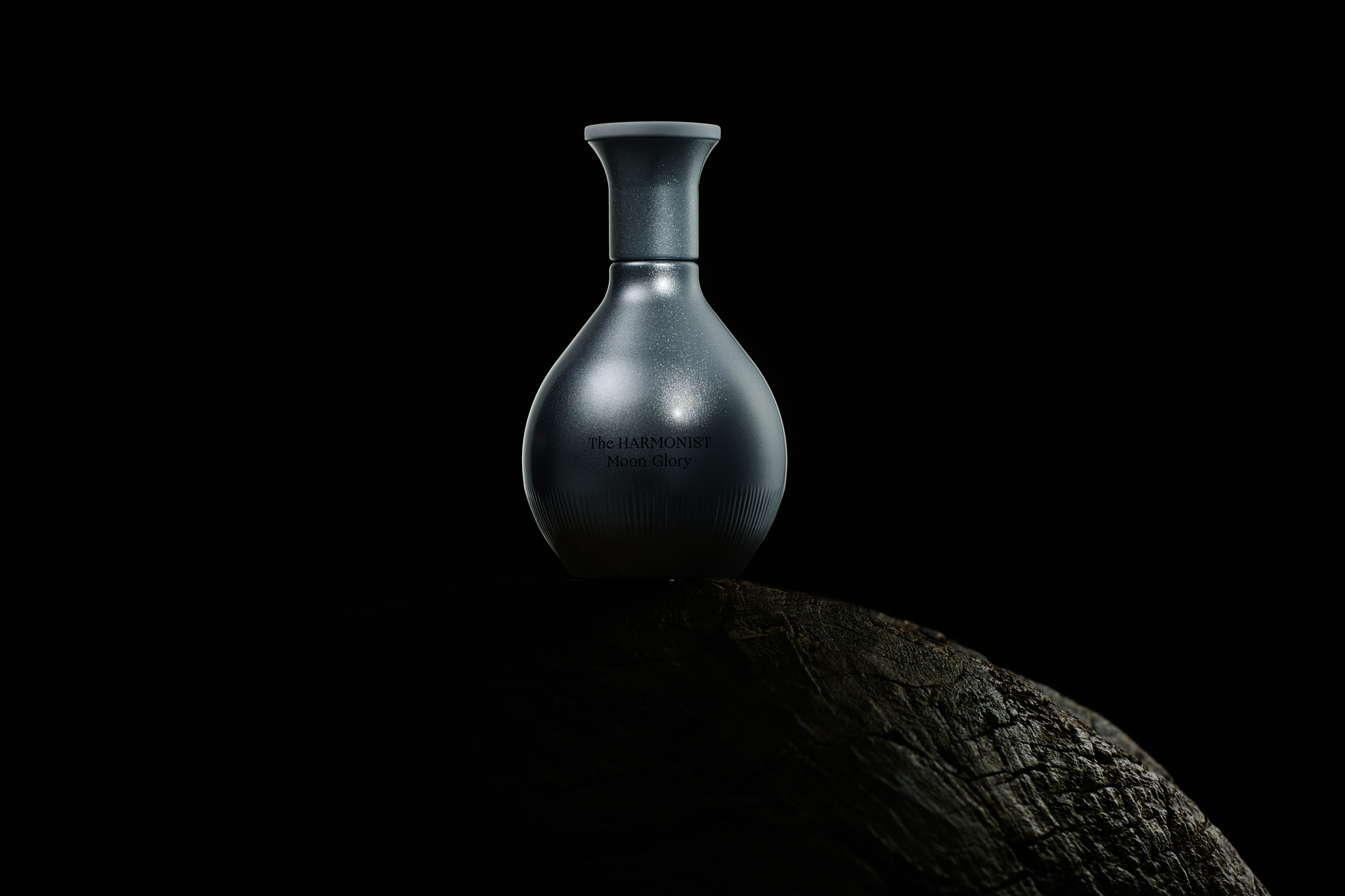Silver textured bottle labeled The Harmonist Moon Glory on a dark textured surface.
